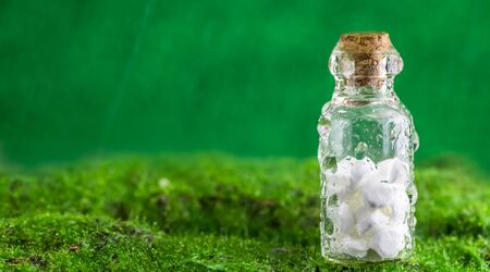 Banner White tablets in a bottle of water droplets on green background. Rain. use, naturalness, homeopathy, natureの写真素材