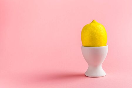 lemon in an egg stand on pink background. concept of Easter, vitamins, health promotion with copy spaceの写真素材