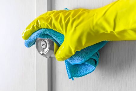 Employees hand in rubber protective glove with rag wiping a wooden door.の写真素材
