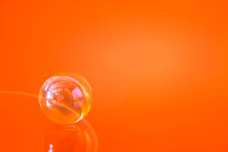 bright orange background glass ball with copy spaceの写真素材