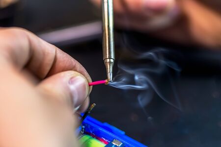 technical master soldering parts with a soldering iron. resin, the smoke, the battery, wires....