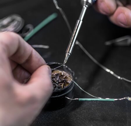 technical master soldering parts with a soldering iron. resin, the smoke, the battery, wires....