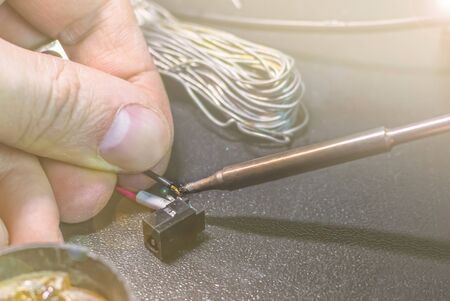 technical master soldering parts with a soldering iron. resin, the smoke, the battery, wires....