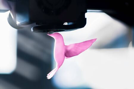The 3D printer prints pink plastic model of hummingbird. modern technology.