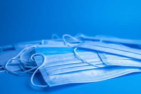 lots of blue disposable medical protective masks on a blue background