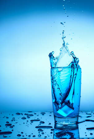 ice cube falls into a glass of waterの写真素材