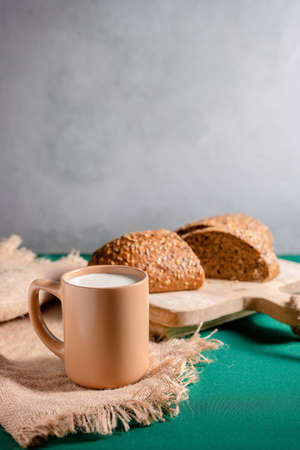 Milk in the glass on green tablecloth. whole-grain bread