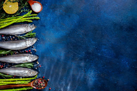 three fish with spices, olive oil on a blue background. top view, flat lay. seafood. with copy space