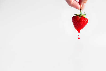 hand holds strawberries, with which red juice drainsの写真素材