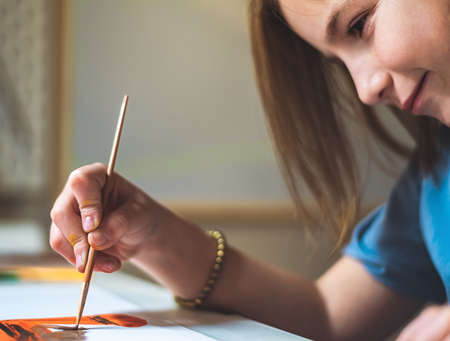 cute girl at home at the table draws with paintsの写真素材