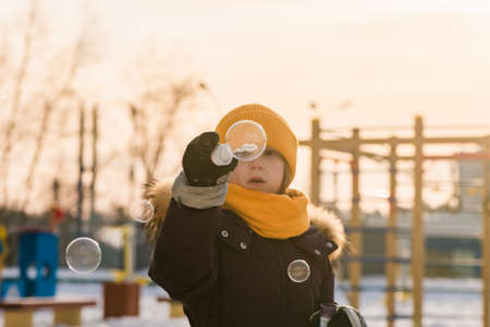 cute girl blows soap bubbles in winterの写真素材