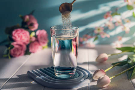 Collagen powder is add to glass of water with a spoonの写真素材