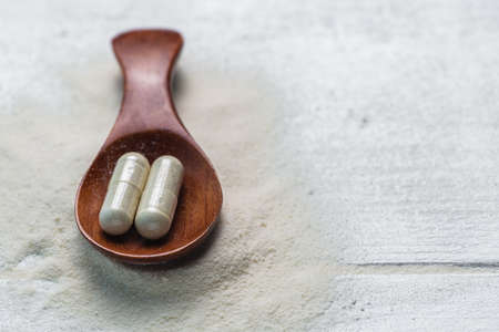 collagen in tablets and powder on wooden white background.の写真素材