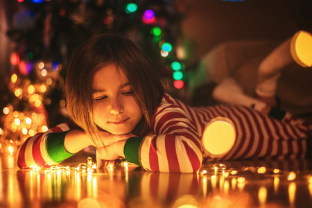 cute girl with garlands in front of the Christmas tree. Indoors, homeの写真素材