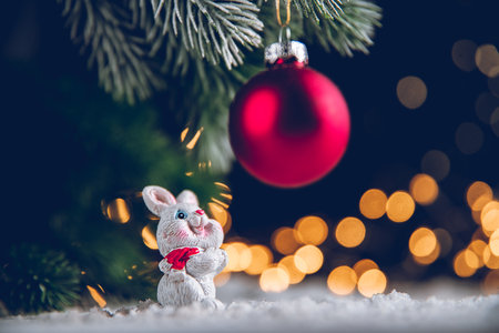 a rabbit symbol of 2023 looks at a red Viva Magenta Christmas ball among the lights, garlands, Christmas trees, chinese calendar year symbolの写真素材