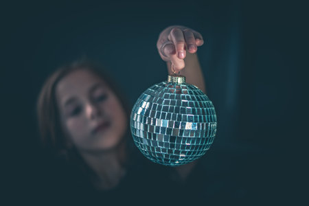 cute girl holds a disco ball on dark backrgound. celebration, holidayの写真素材