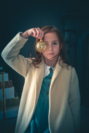 Cute serious girl holding Christmas balls in front of her eyes. new year conceptの写真素材