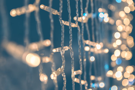Navy blue color blurred background with shiny gold garland lights, winter holiday greeting card,...