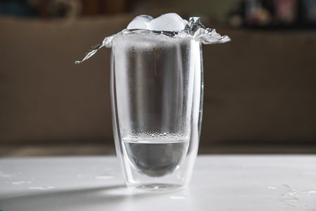 a schoolgirl conducts an experiment with hot water and ice. experience getting clouds in a glass. steam, condensation, homework, studyの写真素材