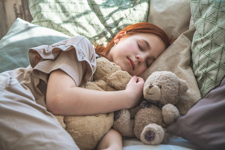 beautiful cute little girl sleeping peacefully and hugging her stuffed toys in bedの写真素材