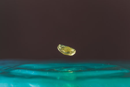 golden Water droplets fall down closely into the blue water, making it the perfect center in natureの写真素材