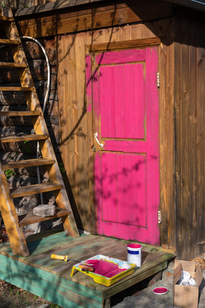 the door of a wooden house painted in a bright purple, pink, fuchsia color. country house, country lifeの写真素材