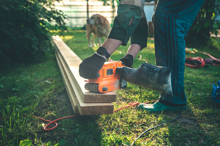 The man grinds the boards with a belt grinder, the electric tool for grinding and polishing the...