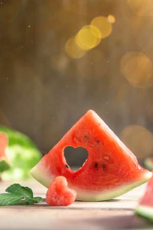 A cut piece of watermelon with a heart-shaped hole. concept Summer, joy, happiness, delicious foodの写真素材