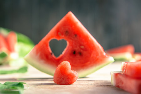 A cut piece of watermelon with a heart-shaped hole. concept Summer, joy, happiness, delicious foodの写真素材