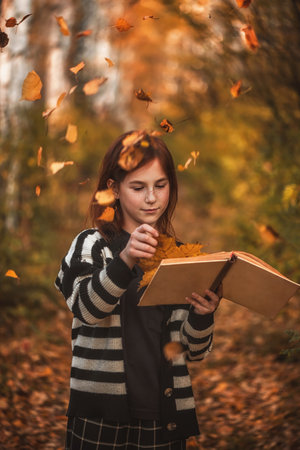 girl with freckles with a book among autumn leaves. reading, magic autumnの写真素材