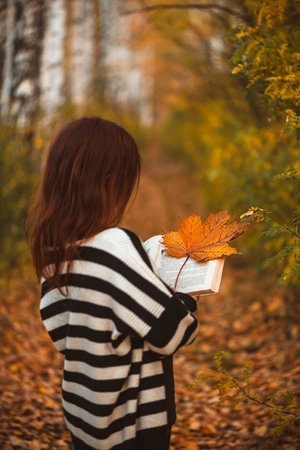 girl with freckles with a book among autumn leaves. reading, magic autumnの写真素材