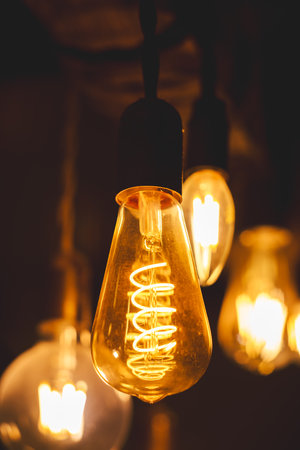Spiral Retro LED light bulbs hanging on a dark background in interior. Electricity, Vintage