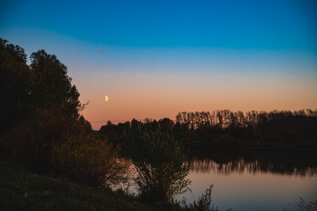 Beautiful view of the autumn nature, the river at sunset and moon