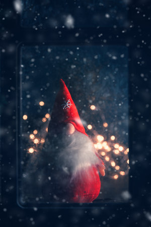Christmas, new year, winter composition. Christmas Gnome behind a frozen window with frosty patternsの写真素材