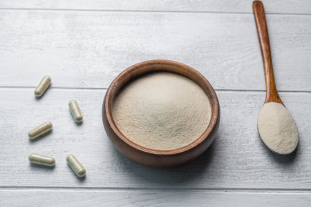 Collagen powder in bowl and spoon on wooden white background. Extra protein intake. Natural beauty and health supplement. Flat lay, top viewの写真素材