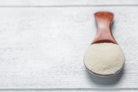 Collagen powder in spoon on wooden white background. Extra protein intake. Natural beauty and health supplement. Flat lay, top viewの写真素材