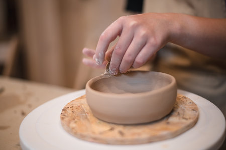 Woman hands, pottery studio and painting cup in workshop for sculpture, creative manufacturing or design. Painter, ceramics product and brush process, artistic pattern or production in small businessの写真素材