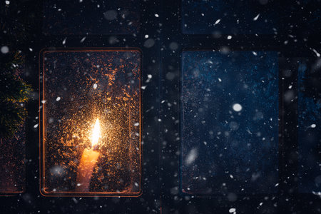 Christmas, new year, winter composition. Candle behind a frozen window with frosty patterns, copy spaceの写真素材