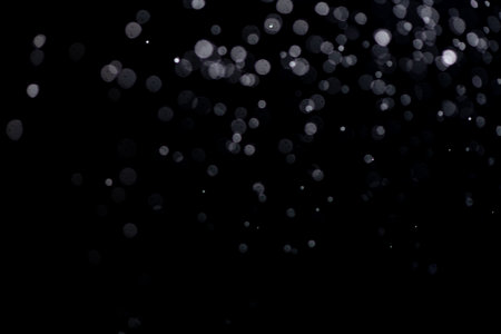 Snowstorm texture. Bokeh lights on black background, shot of flying snowflakes in the airの写真素材