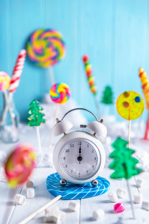 Alarm clock with lollipops and candy on wooden backgroundの写真素材