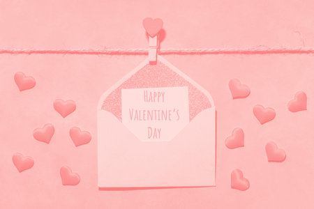 tinted photograph, pink, peach fuzz color. clothespin with heart on a rope on a pink background. postcard with text happy valentines day on paper. flat lay, top view, Love, Valentine's Day February 14の写真素材