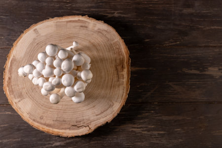 Closeup of a bunch of shimeji mushrooms on a tree cut, on wooden, dark background, top view,...