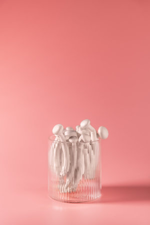 Closeup of a bunch of shimeji mushrooms in glass, on pink background, superfood, a type of delicious...