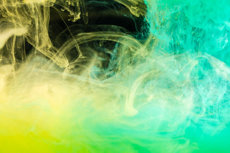 clouds of yellow and green smoke on black background, clouds of paint in water, aquarium, abstract background, textureの写真素材