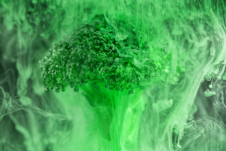 Fresh broccoli with a cloud of green color paint in water. Artistic nutrition concept. Science of food action photography. Creative concept of vegetarianism, benefits of vegetablesの写真素材