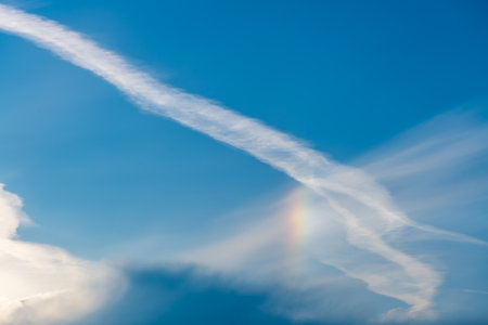 Sky with cirrus, stratus clouds, airplane trail and halo from the sun, rainbow, sky with clouds, natural background, celestial landscape, sky backgroundの写真素材