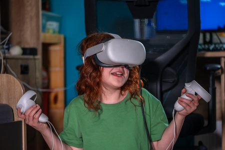 redhead teen girl at home in living room put on vr helmet to enjoy virtual reality online game cyber space world simulation. cute girl has fun using new electronic device for entertainmentの写真素材