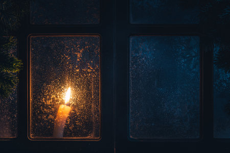 Christmas, new year, winter composition. Candle behind a frozen window with frosty patterns, copy spaceの写真素材