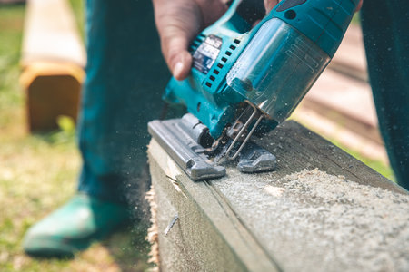 A man, a worker with an electric jigsaw, a renovator saws a wooden board, DIY, construction