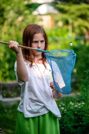 Cute girl catching butterflies with a net in summer, summer time, vacation, summer funの写真素材